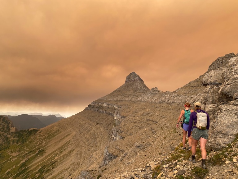 Burnt orange skies from wildfire smoke give a surreal backdrop for pika surveys. Lexie and Maloree hike in the foreground.