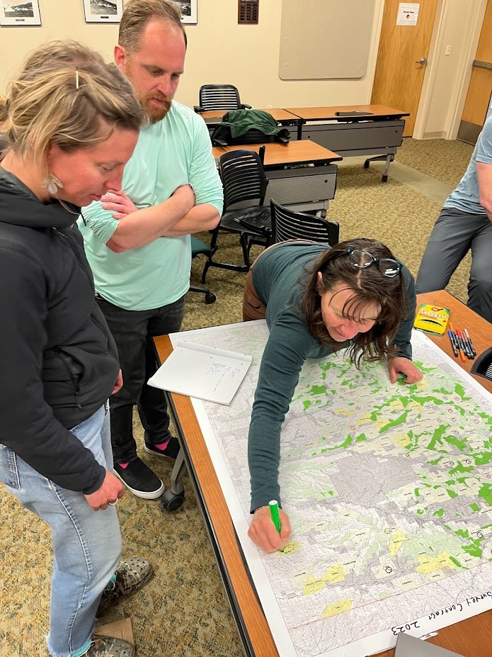 Ceeanna Zulla and Nick Kryshak look on as Shaula Hedwall marks up a map during a Mexican spotted owl survey coordination meeting in Alamogordo, New Mexico.