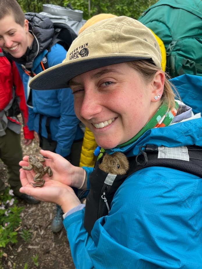 Maloree with a Boreal Toad while Rat LePika looks on from her shoulder pouch in Glacier National Park, Montana.