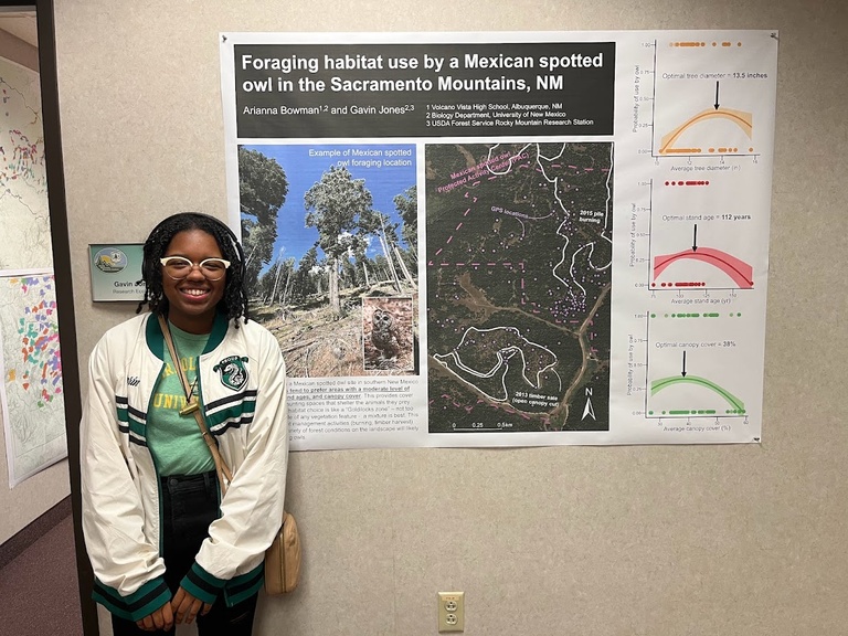 Arianna Bowman (high school intern) poses with a poster summarizing her summer research project.