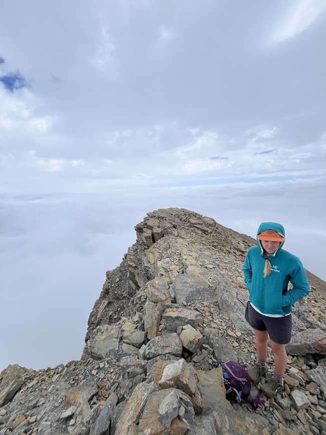 Dani Owens above the clouds on the summit of Mt. James in Glacier National Park.
